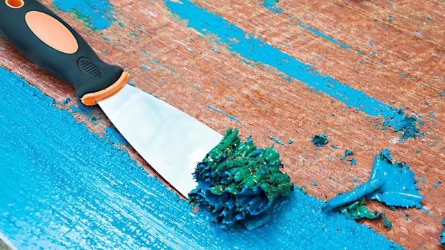 Sử dụng dao cạo để loại bỏ các vết sơn dính trên sàn