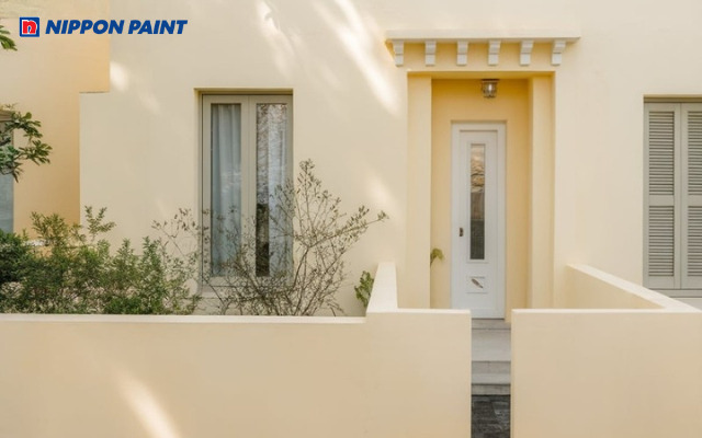 Màu sơn nhà vàng kem nhạt hòa quyện cùng cây xanh, tạo không gian hiện đại và thư thái