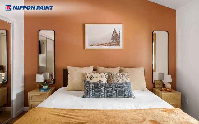 Sơn tường phòng ngủ màu cam đất trầm kết hợp giường và bàn đầu giường tối màu sang trọng